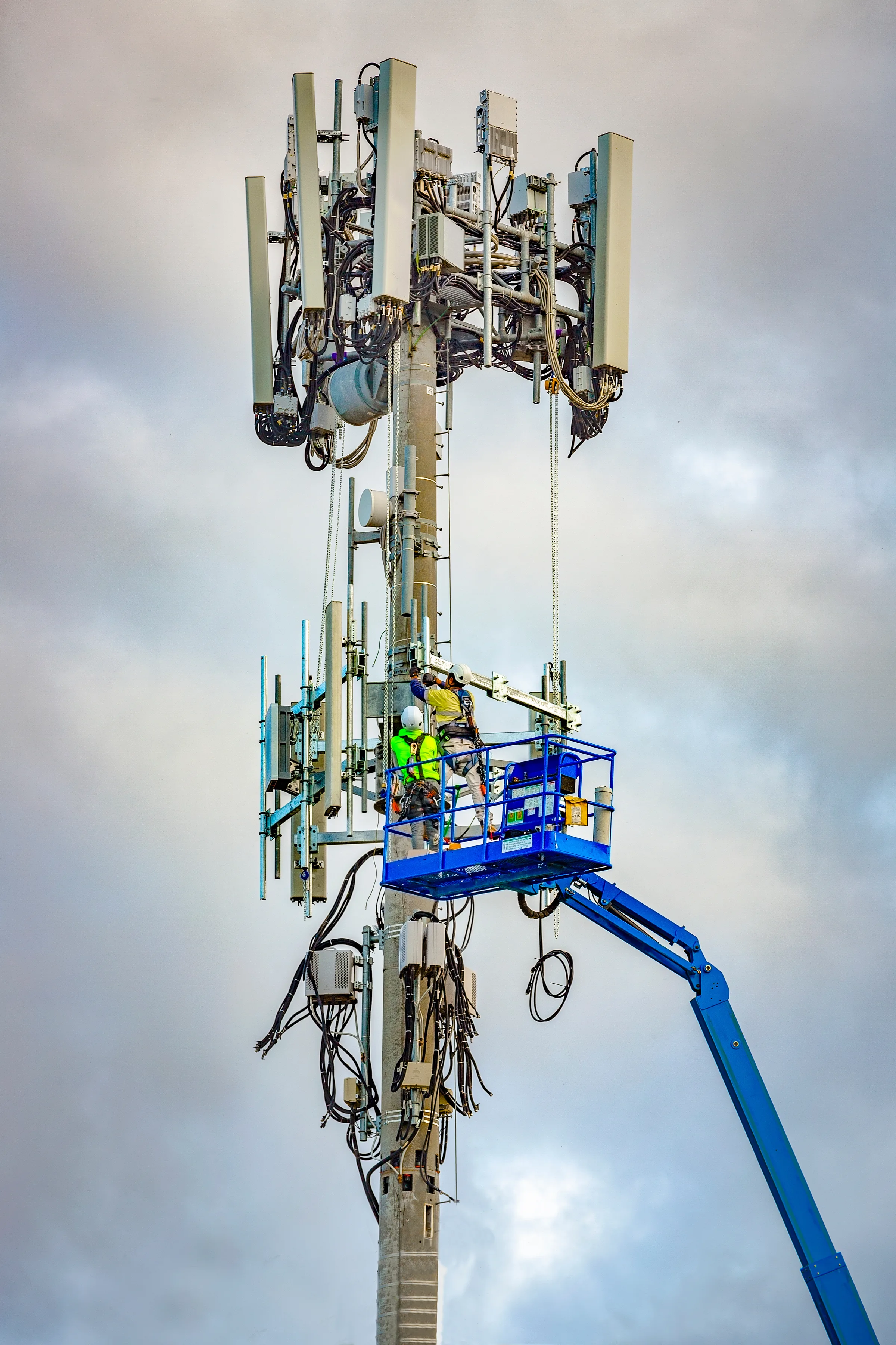 Technicians on a lift working on a telecommunications tower