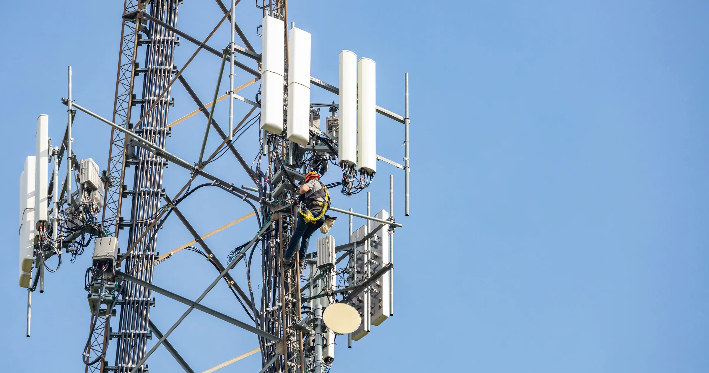Technician working on a telecommunications tower among panel antennas
