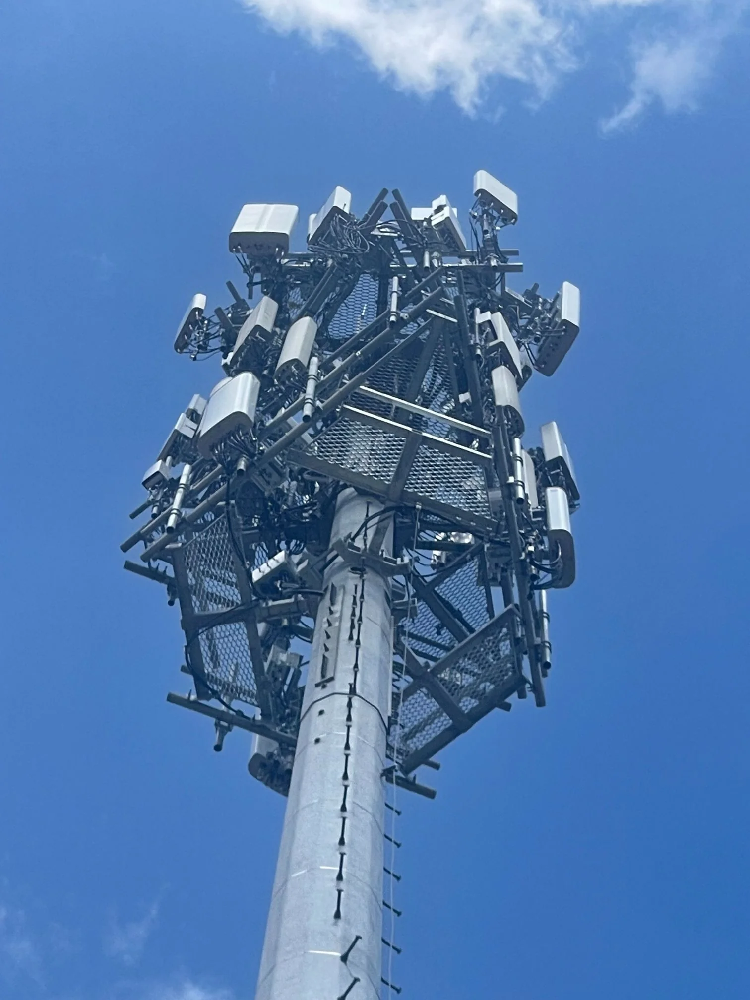 Monopole telecommunications tower with panel antennas against a blue sky