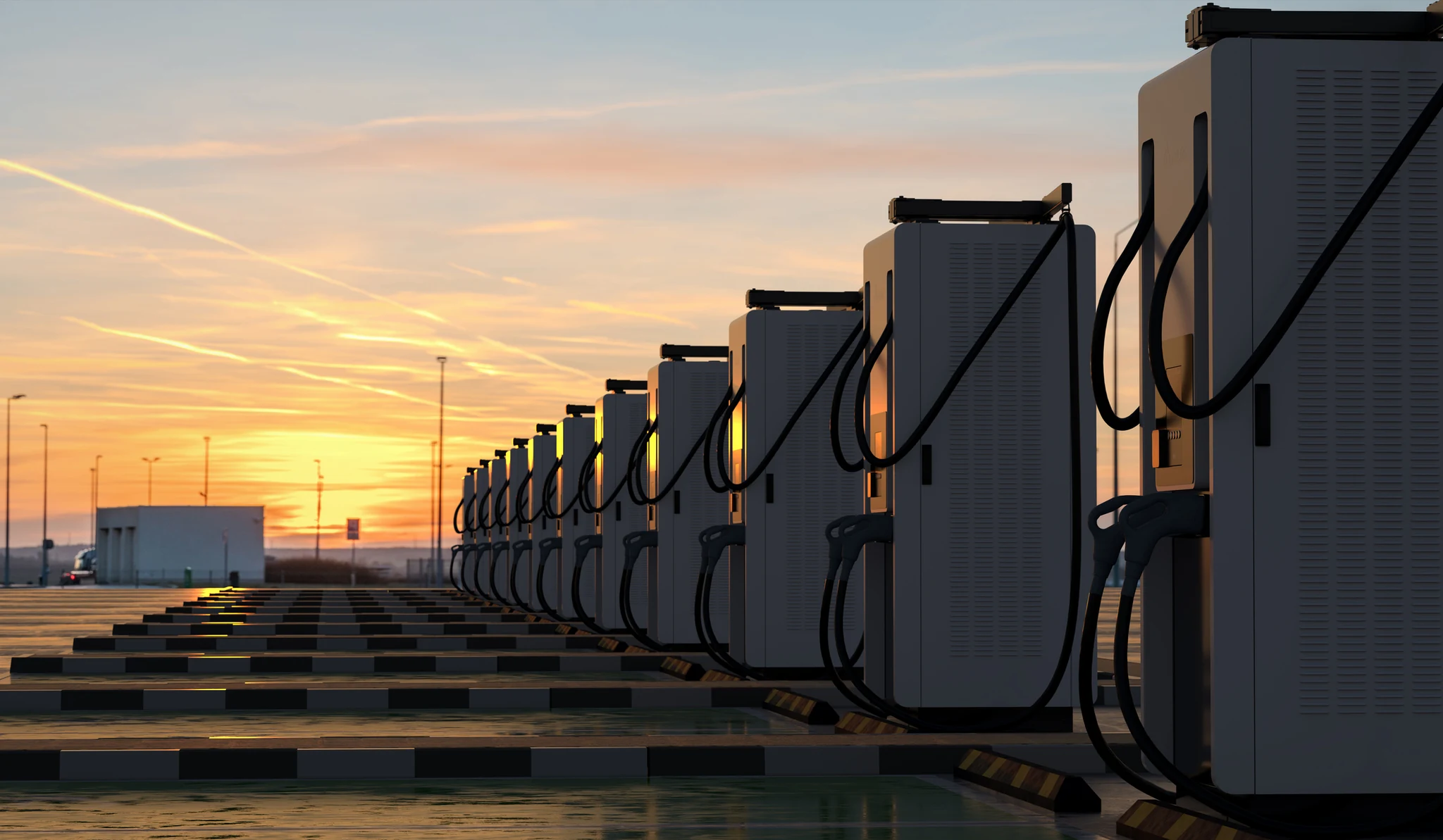 A row of electric vehicle charging stations at sunset